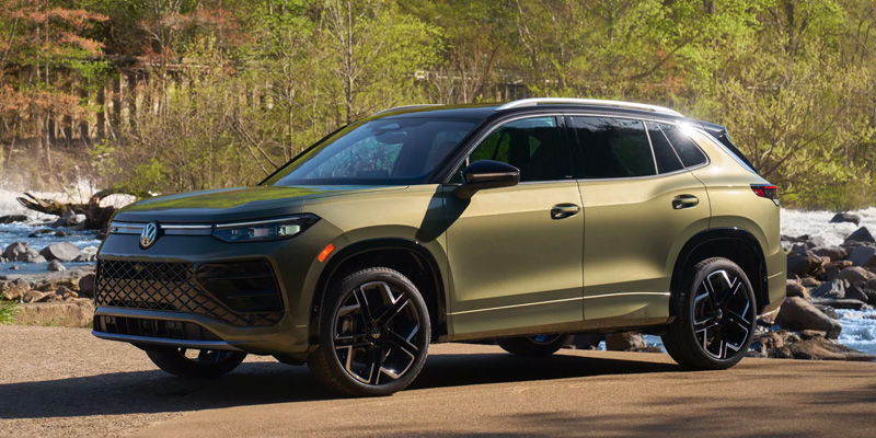 A Volkswagen Tiguan parked near a scenic river with lush greenery in the background.